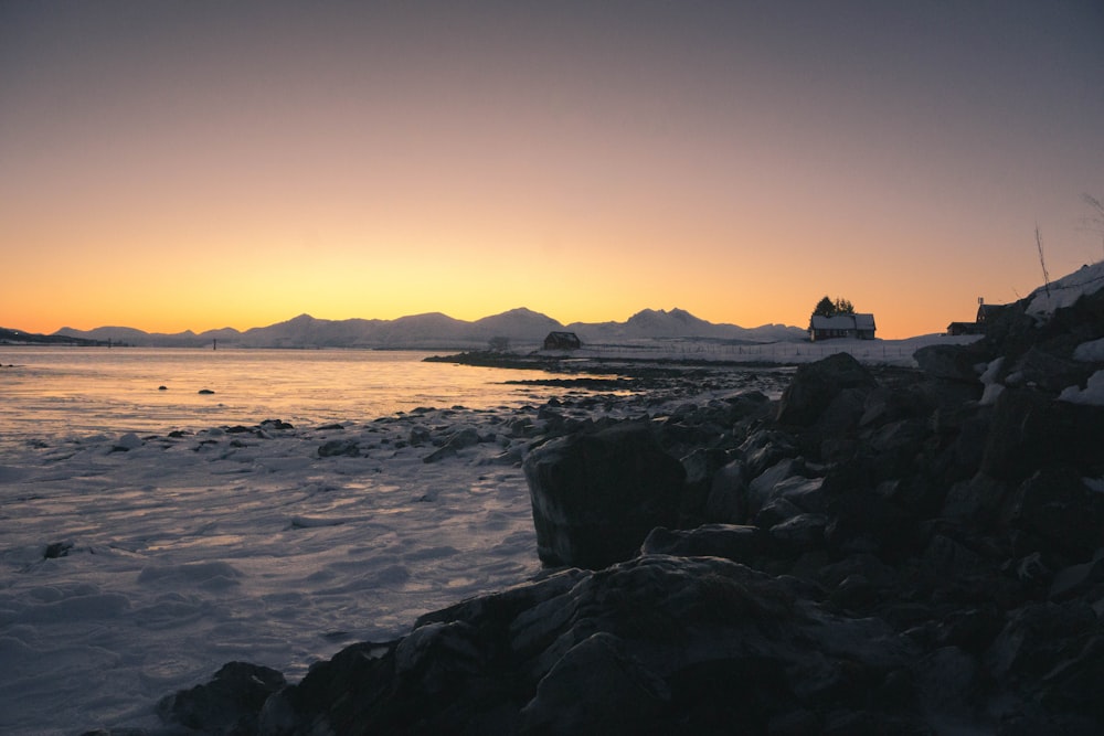 the sun is setting over a rocky beach