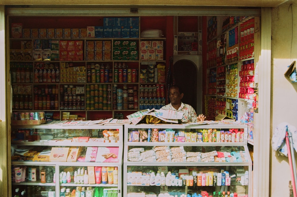 a man standing behind a store filled with lots of food