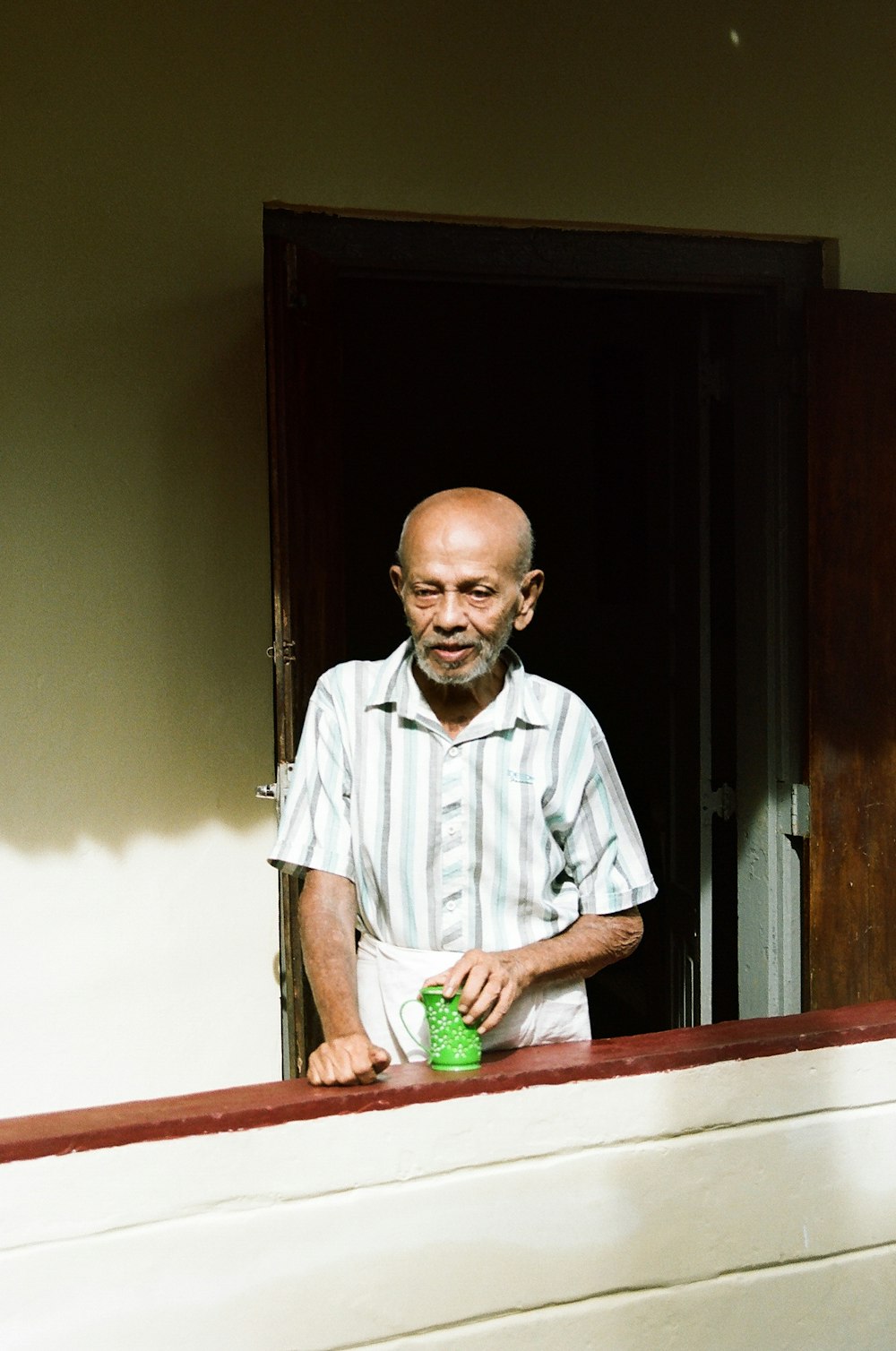 a man standing in a doorway with a green cup