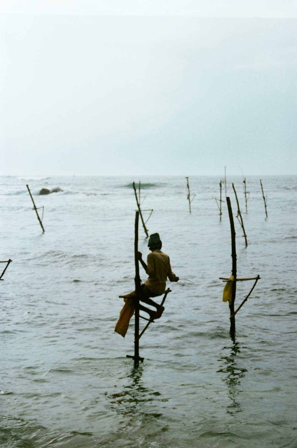 a man sitting on a pole in the middle of the ocean
