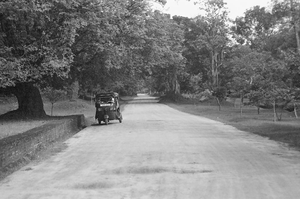 a black and white photo of a truck driving down a road