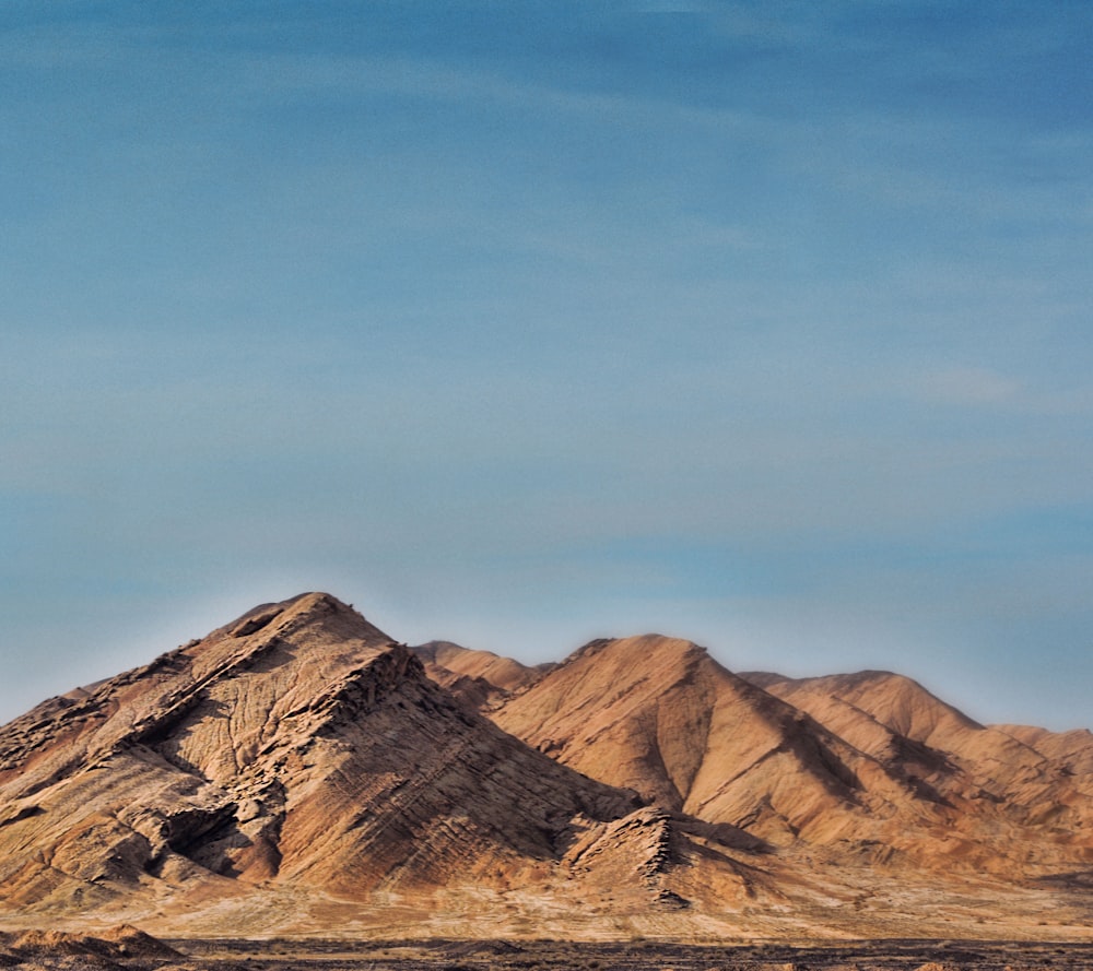 a plane flying over a mountain range under a blue sky