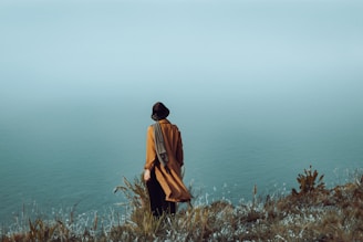 a person standing on a hill overlooking a body of water