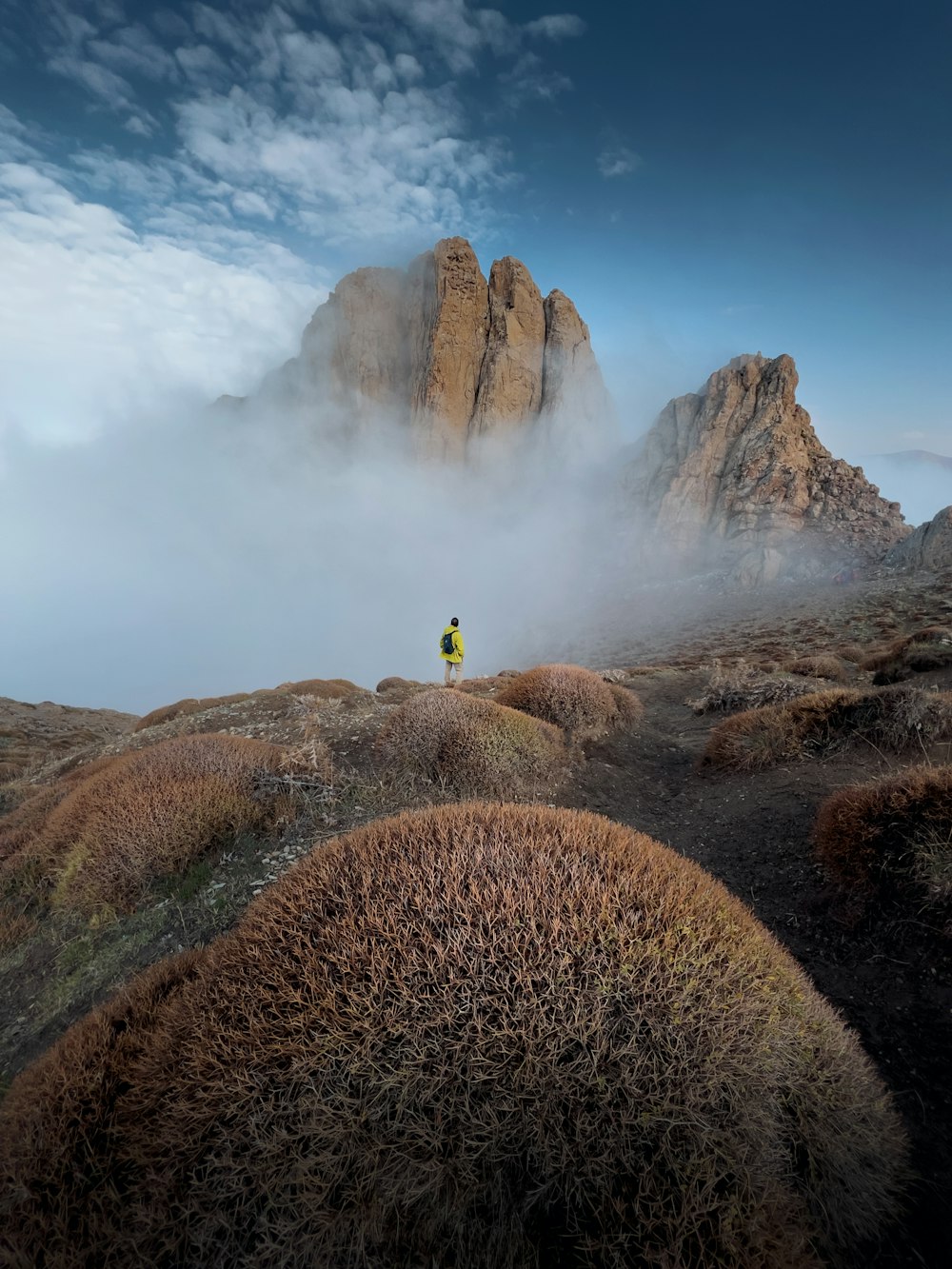 une personne debout au sommet d’une montagne entourée de brouillard