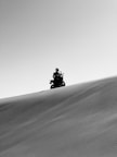 a man riding a motorcycle down a sand dune