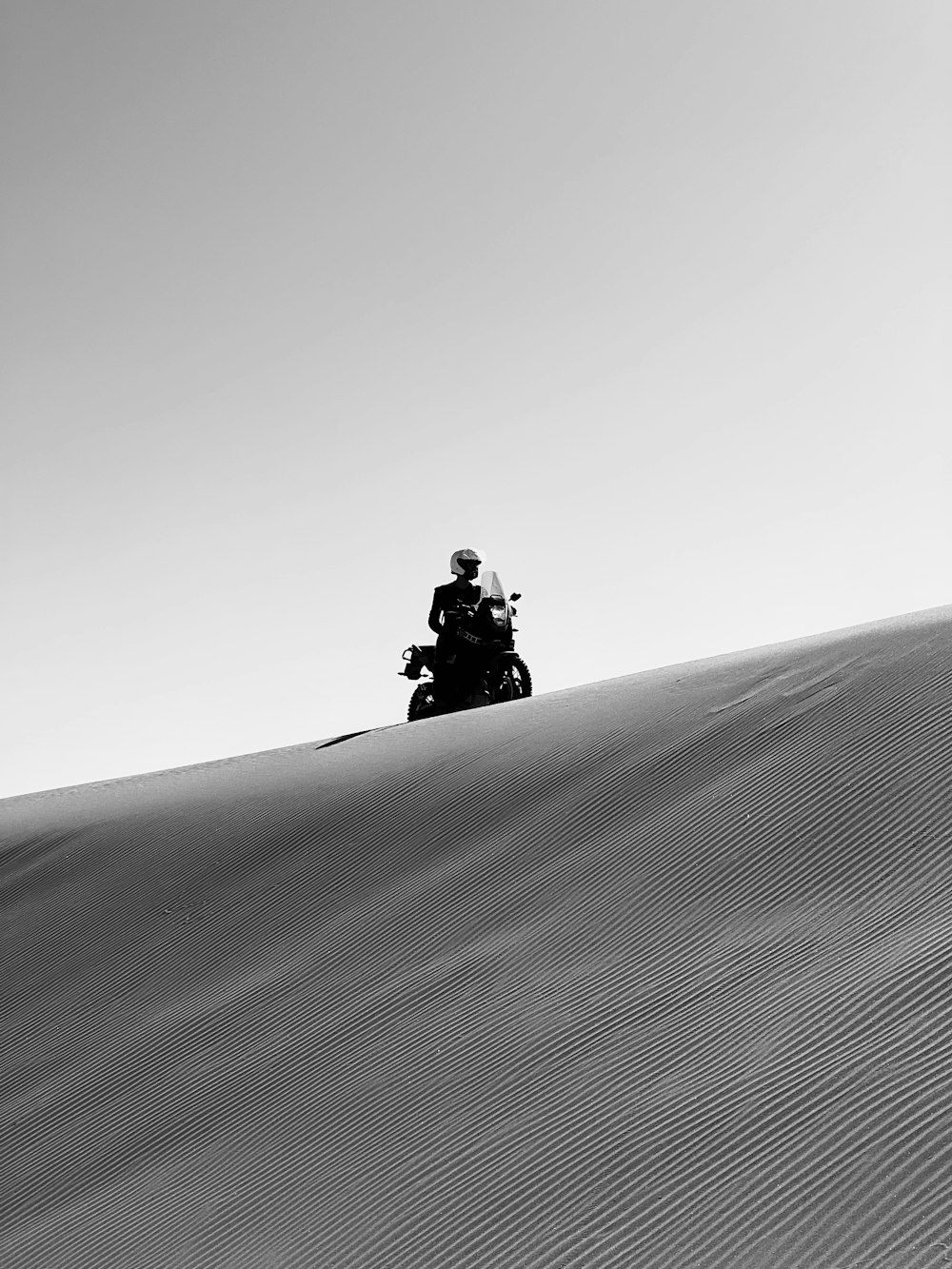 un uomo in sella a una motocicletta lungo una duna di sabbia