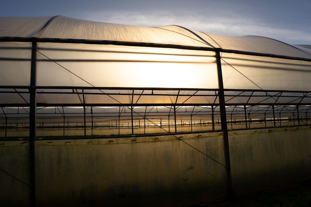 the sun is setting behind a large greenhouse