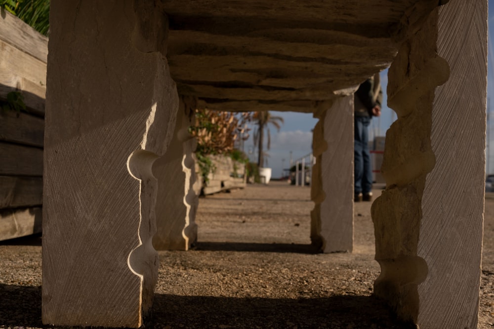 a person standing under a wooden structure on a beach