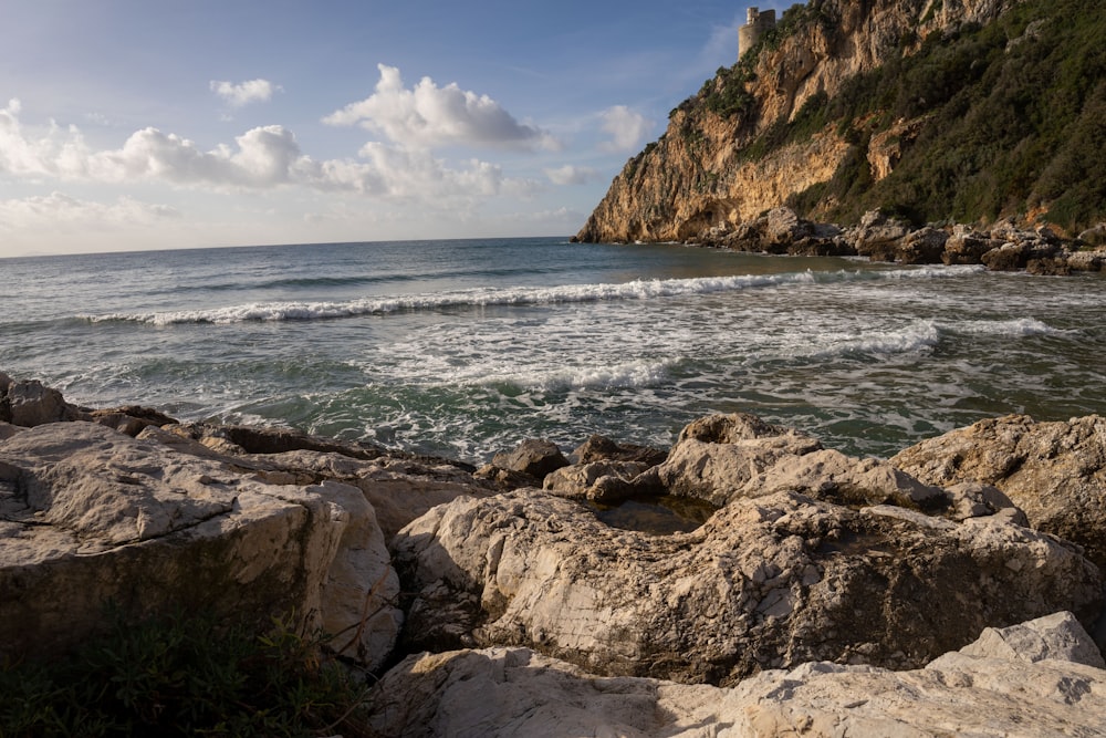 a rocky beach with a cliff in the background