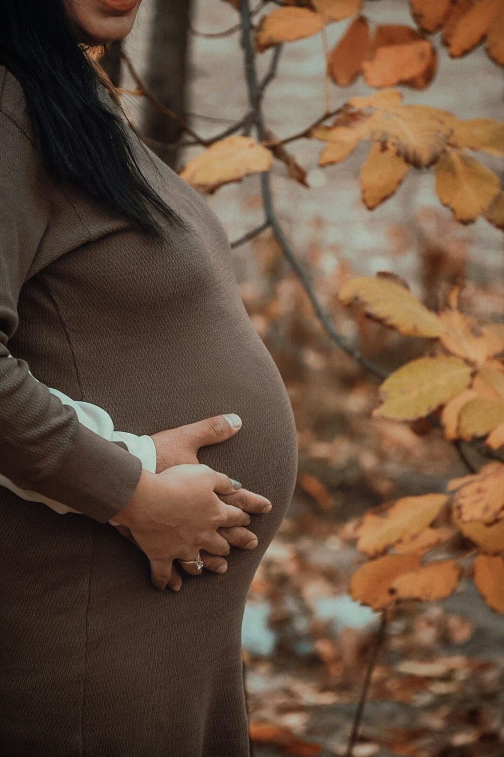 a pregnant woman standing in front of a tree