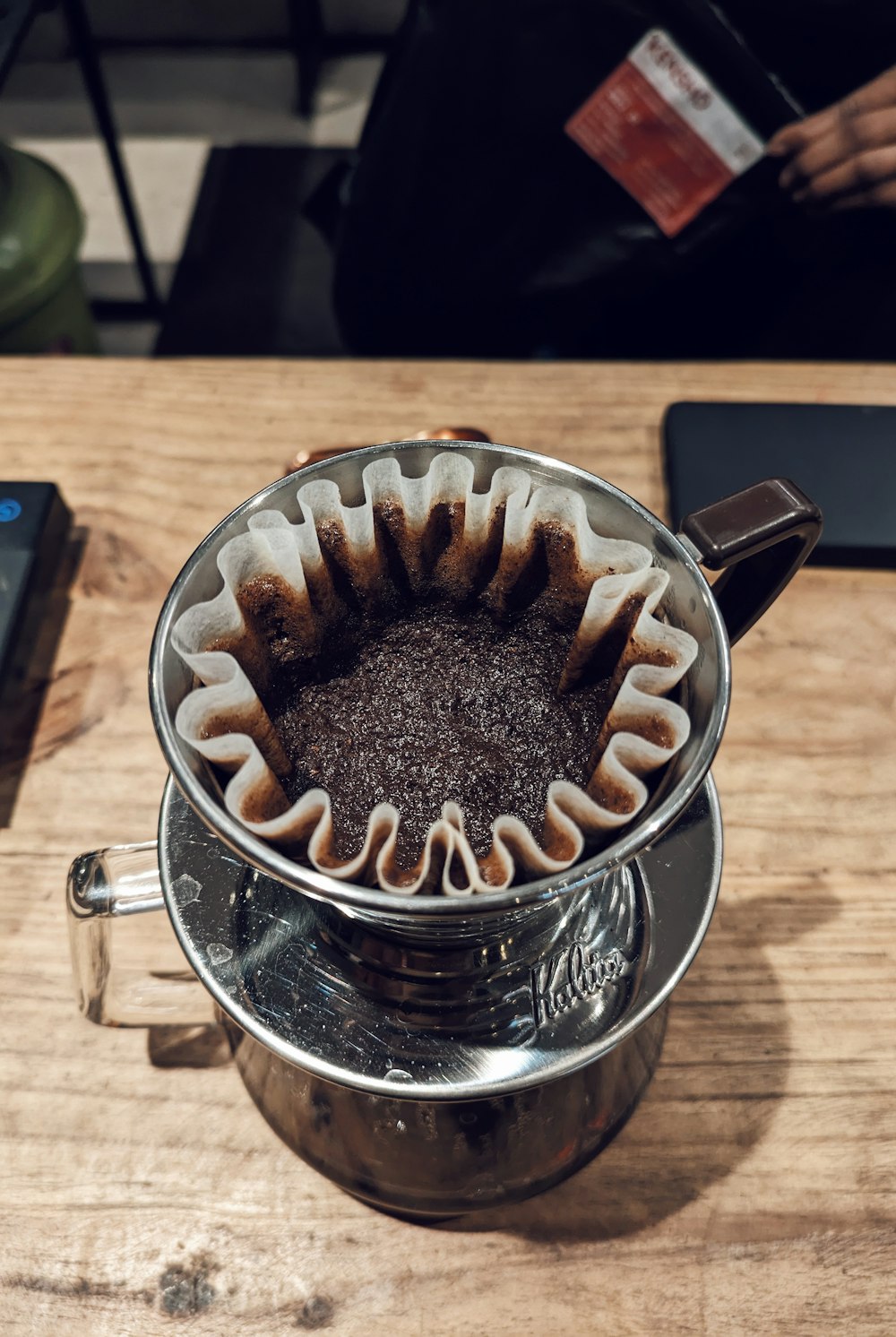 a coffee pot filled with liquid on top of a wooden table
