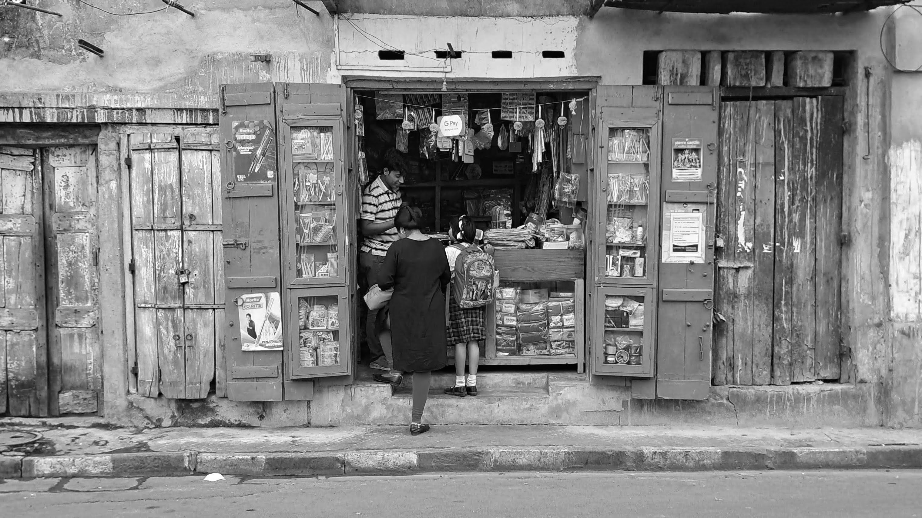a black and white photo of a woman standing outside of a store