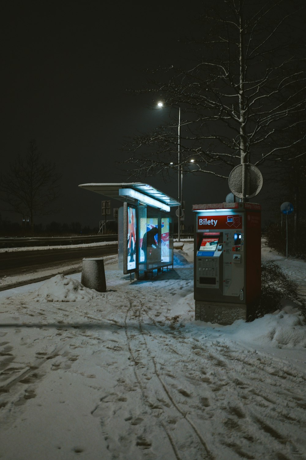a bus stop sitting on the side of a snow covered road