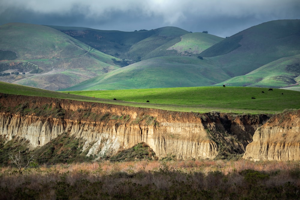 a view of a mountain range with green hills in the background