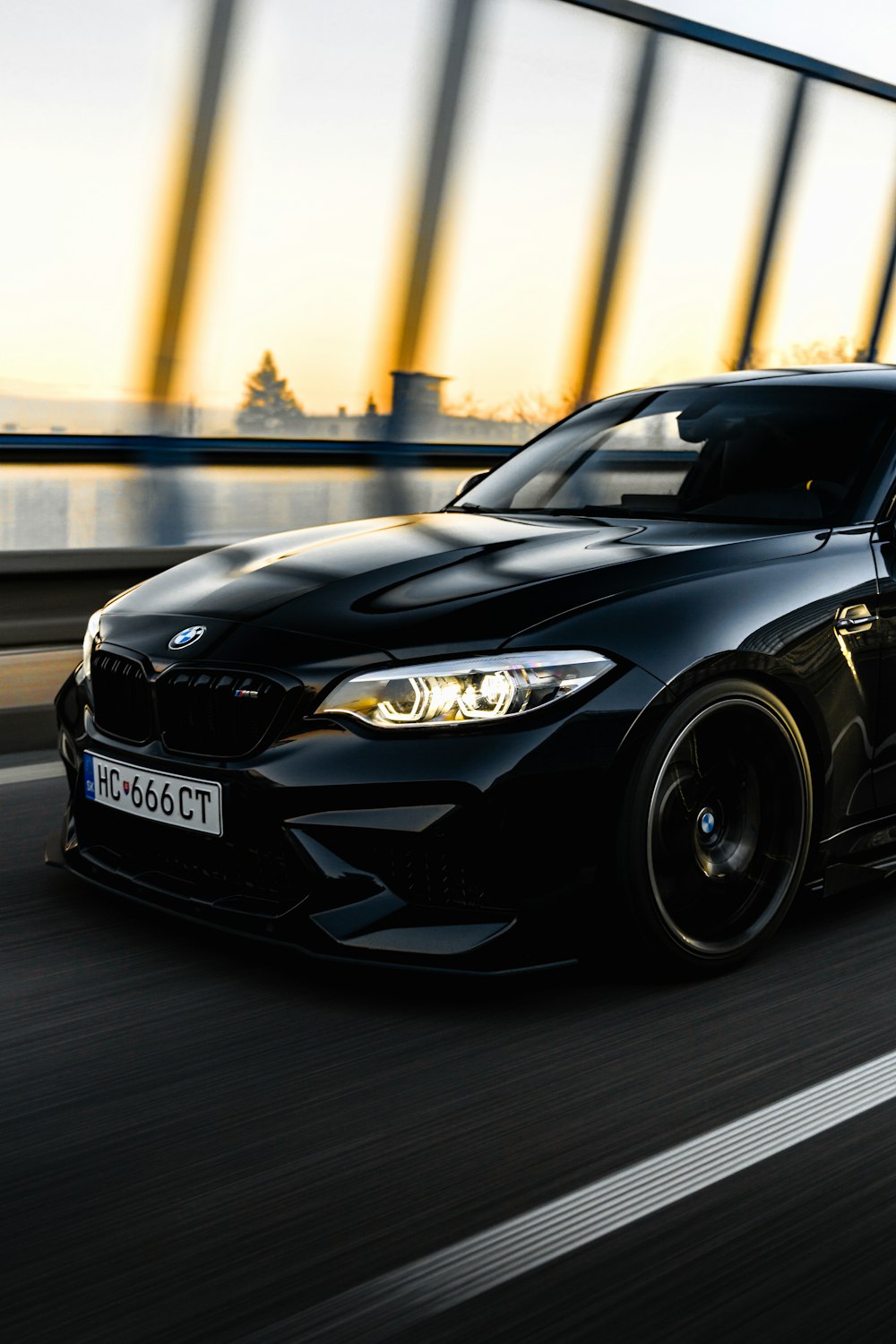 a black car driving down a highway next to a bridge