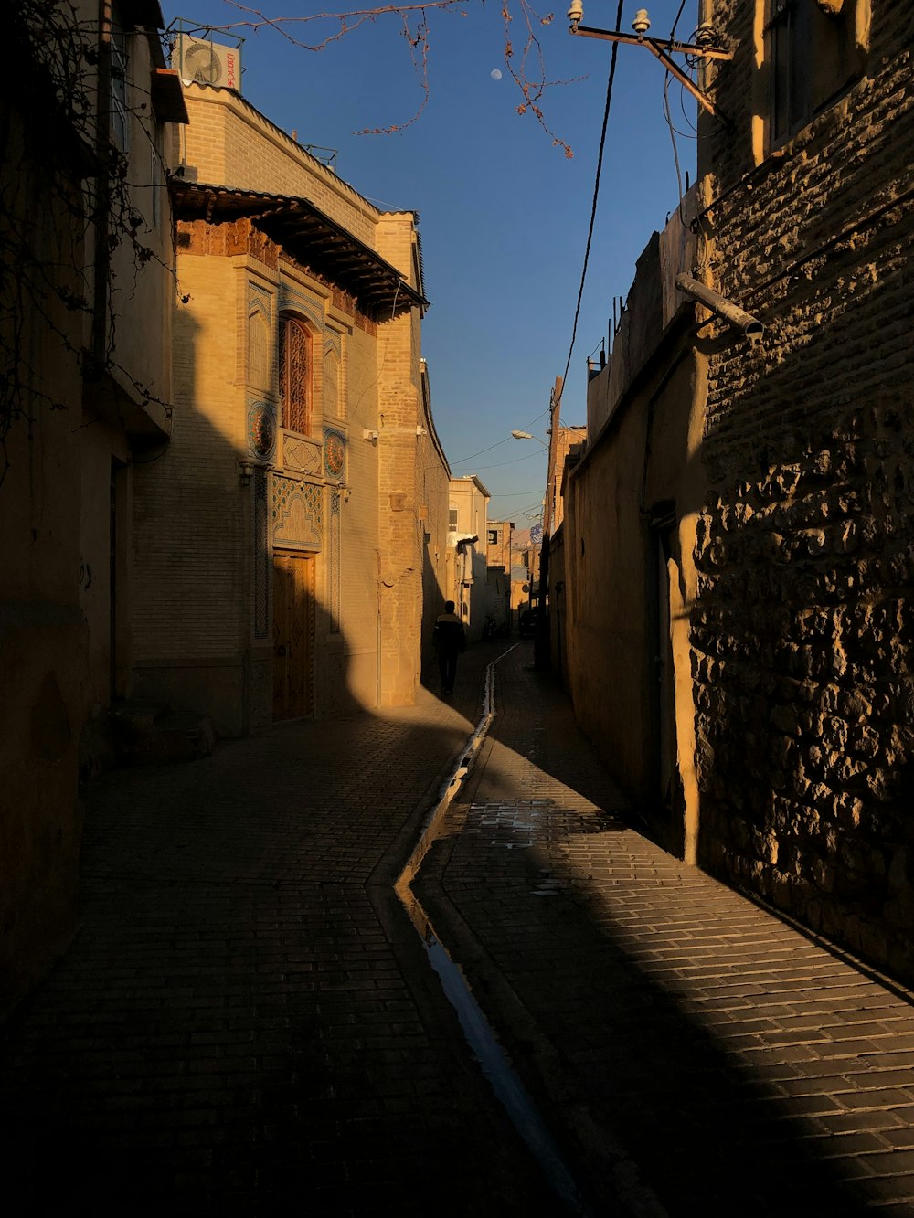 a narrow alleyway with a brick building and cobblestone street