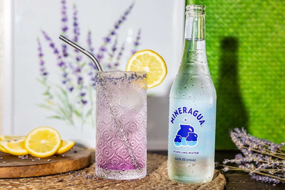 a bottle of lavender water next to a glass with a straw