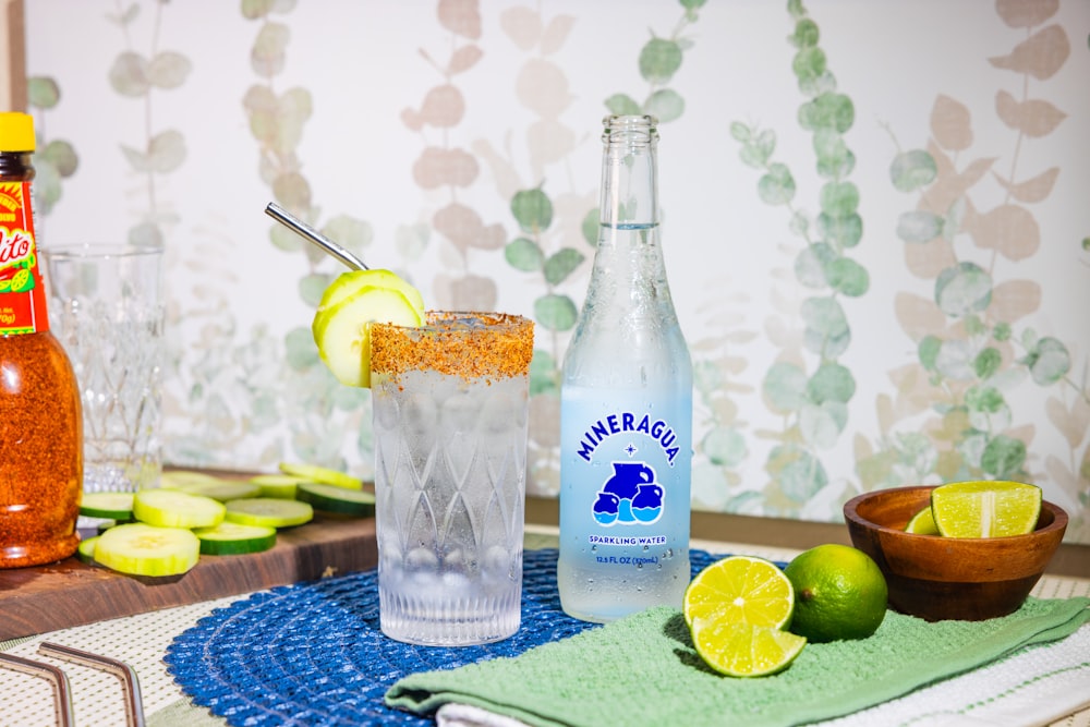 a table topped with bottles of alcohol and a bowl of limes