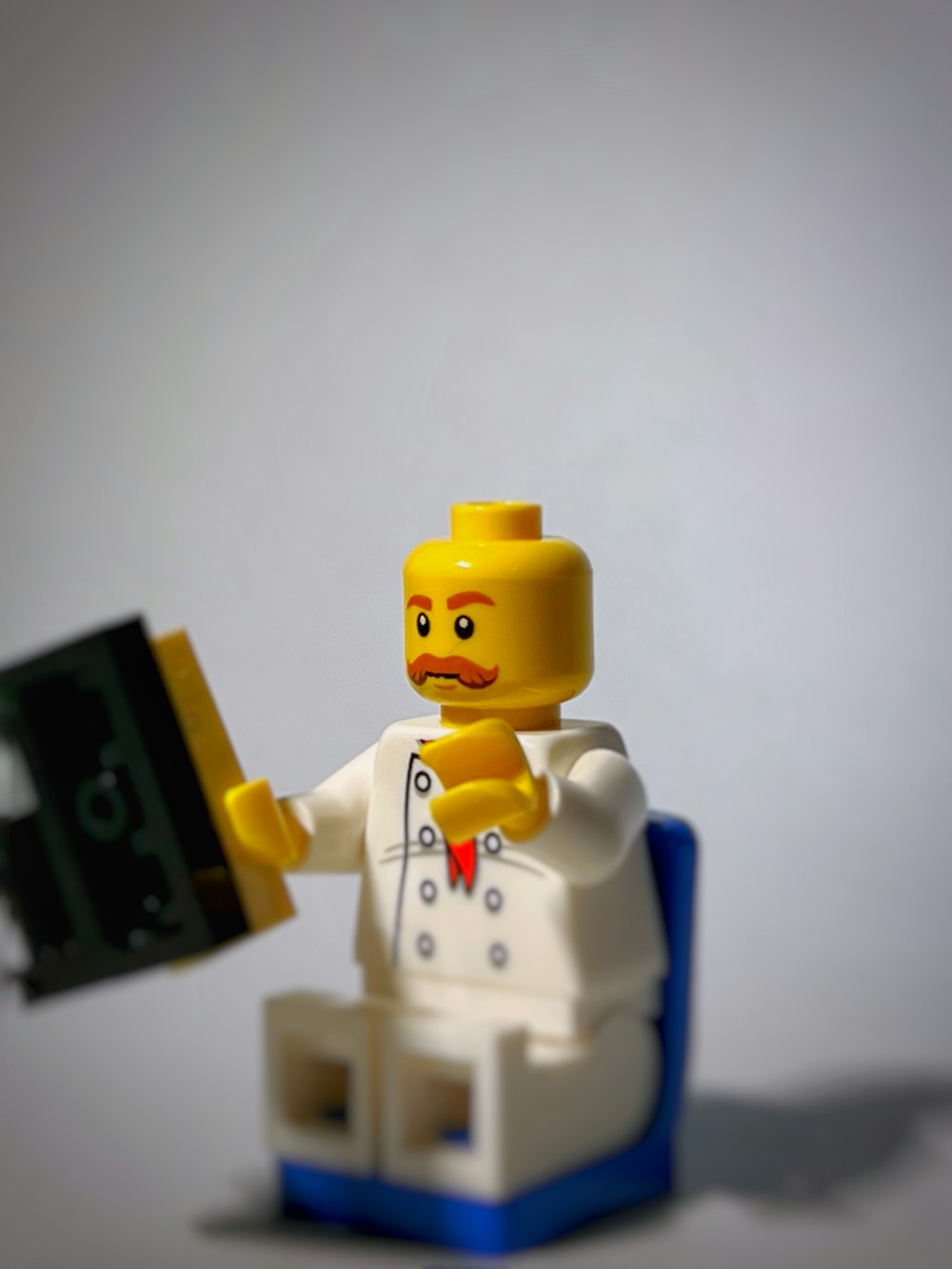 a lego man holding a black object in his hand