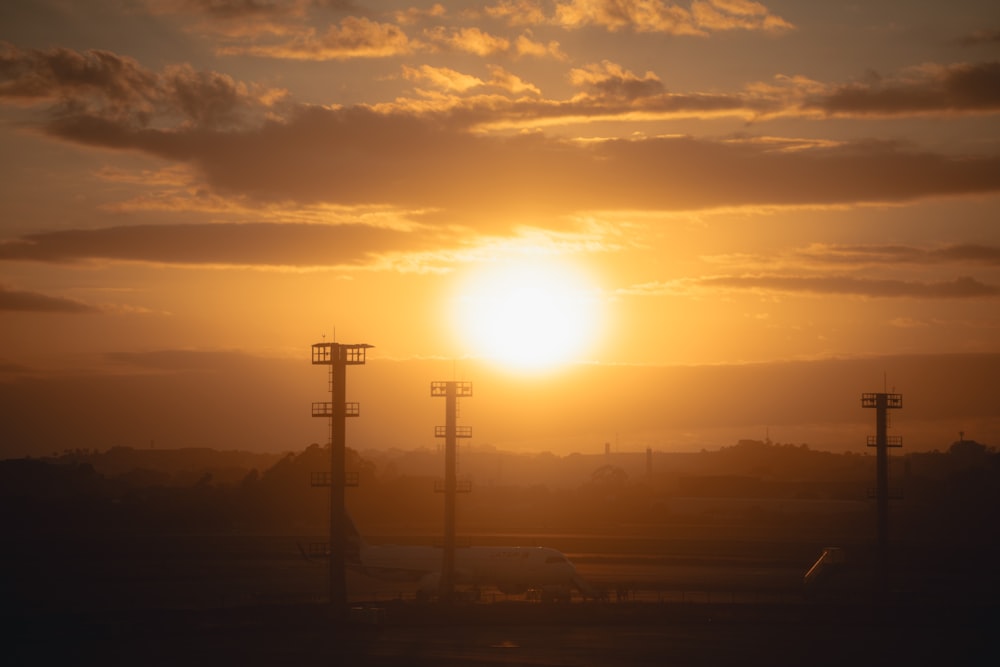 the sun is setting over the airport with a plane in the foreground