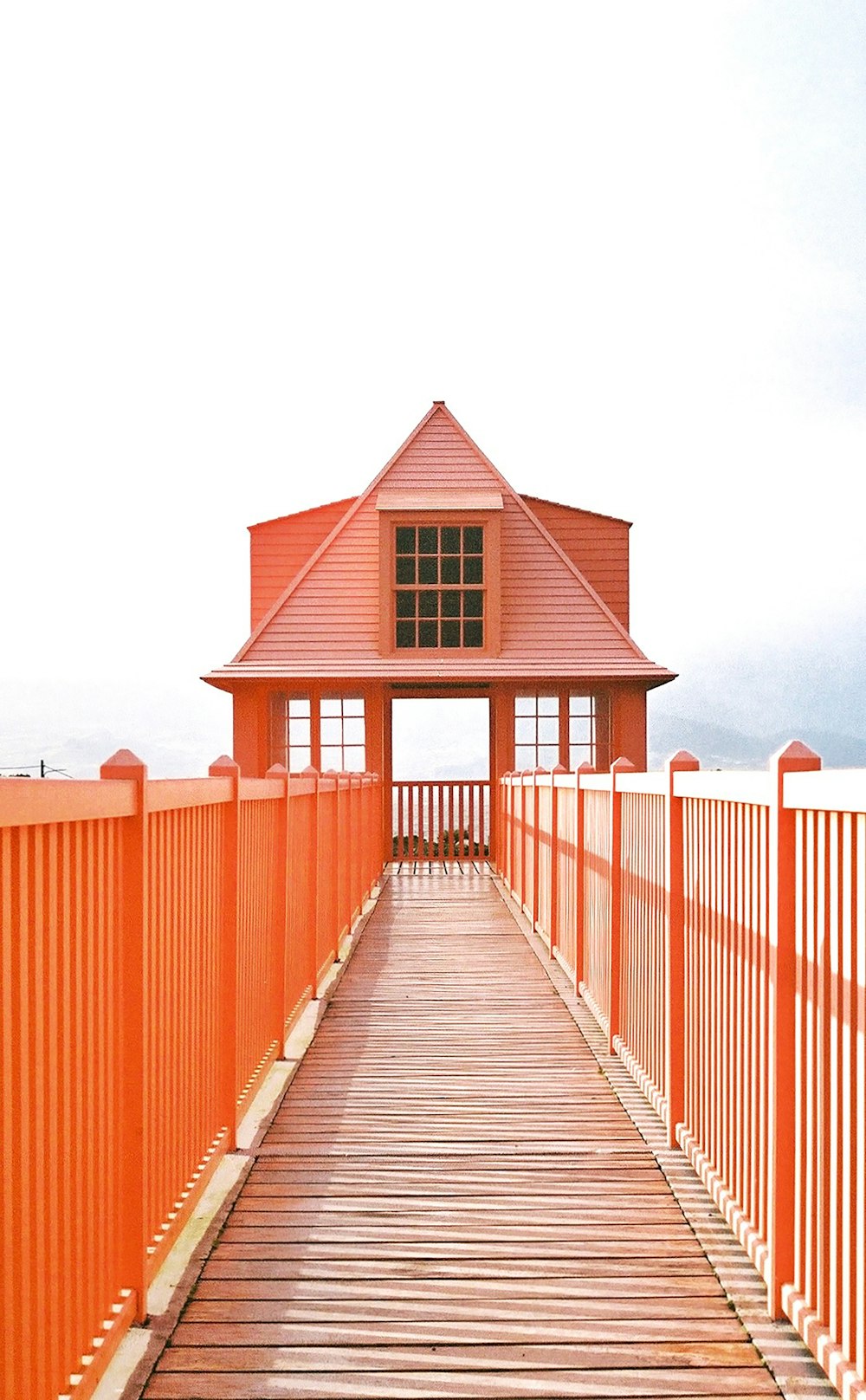 uma passarela de madeira que leva a um edifício laranja