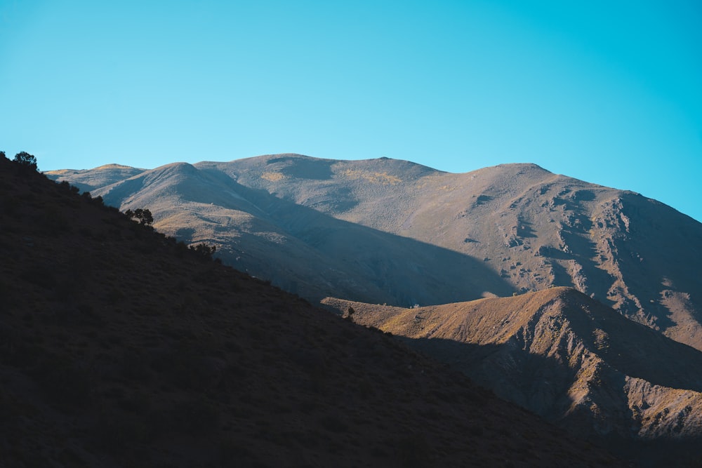 uma vista de uma cordilheira com um céu azul ao fundo