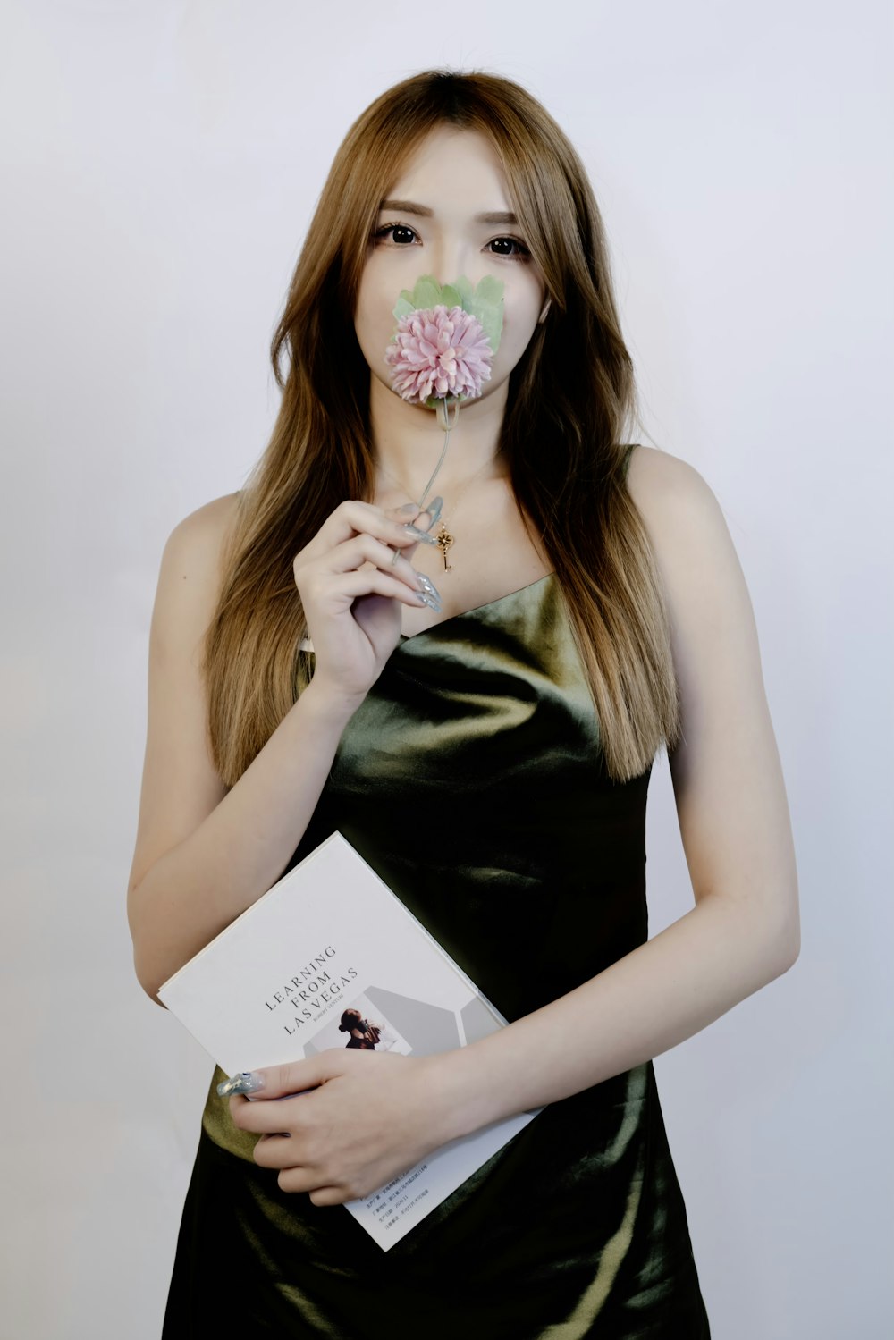 a woman holding a book and a flower in her mouth