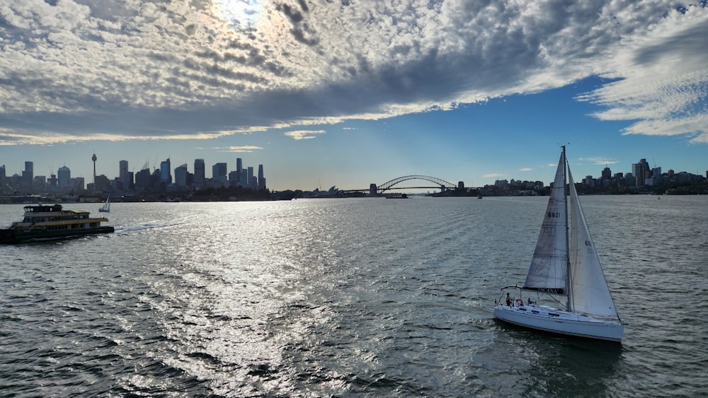 a sailboat in the water with a city in the background