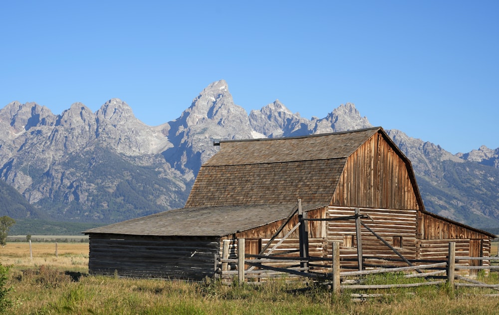 a barn in a field with mountains in the background