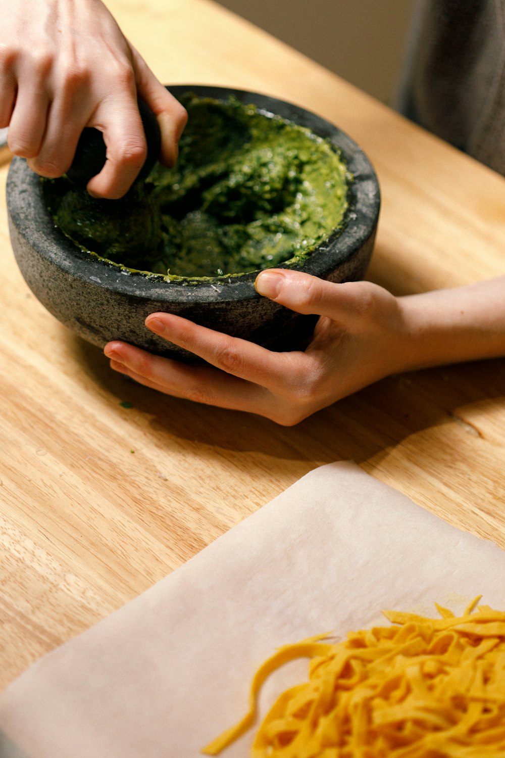 a person holding a bowl of food on top of a wooden table