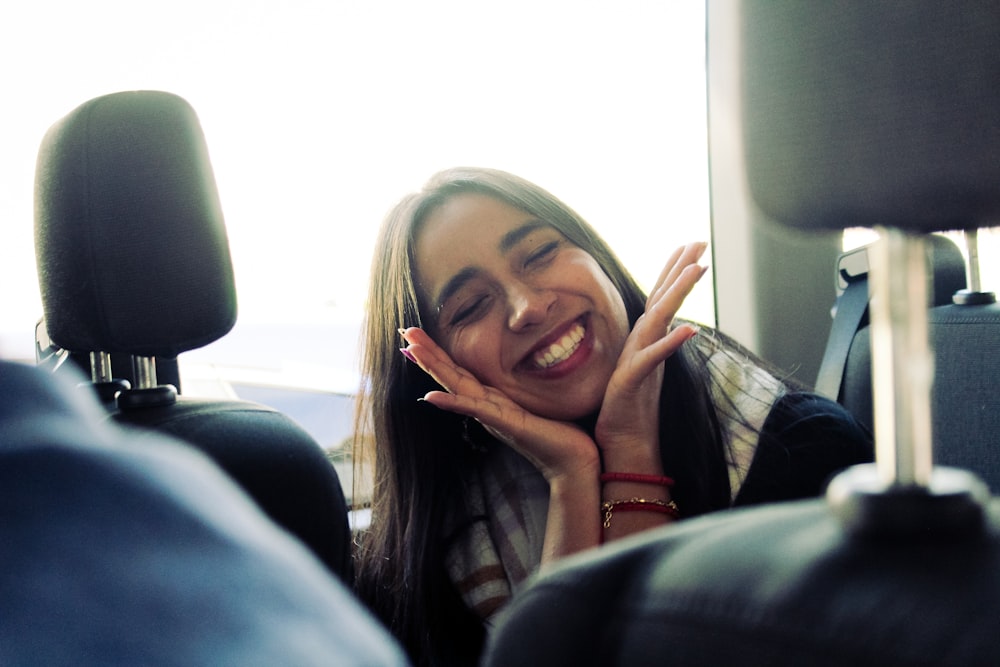 a woman smiles as she sits in the back of a car