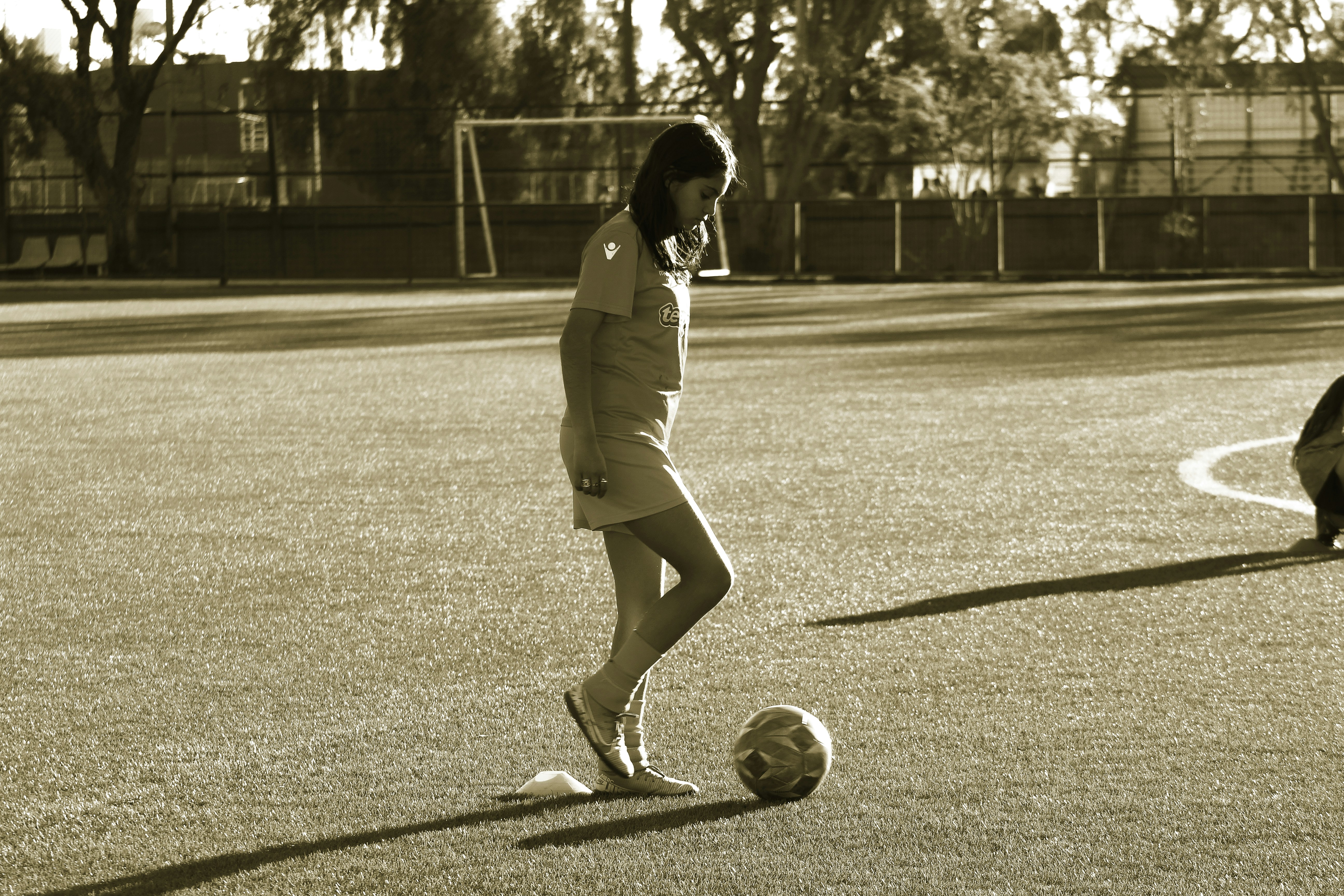 a woman is kicking a soccer ball on a field