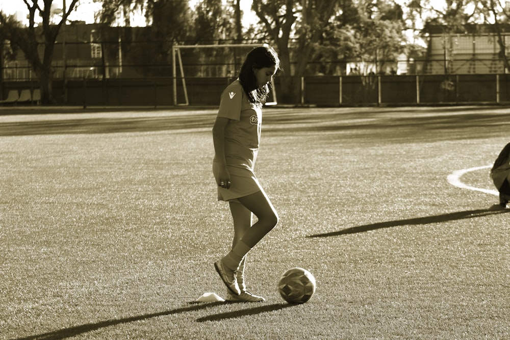 a woman is kicking a soccer ball on a field