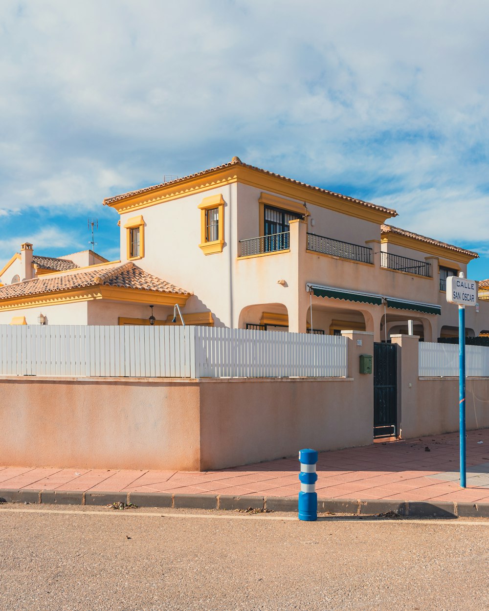 a house with a fence and a blue pole in front of it