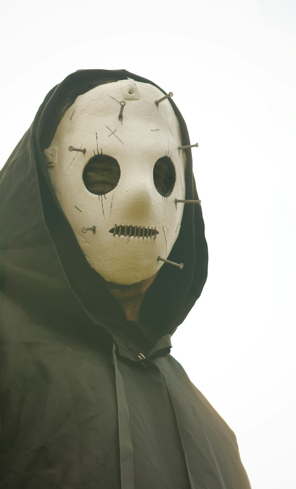 a person wearing a white mask with a black hood