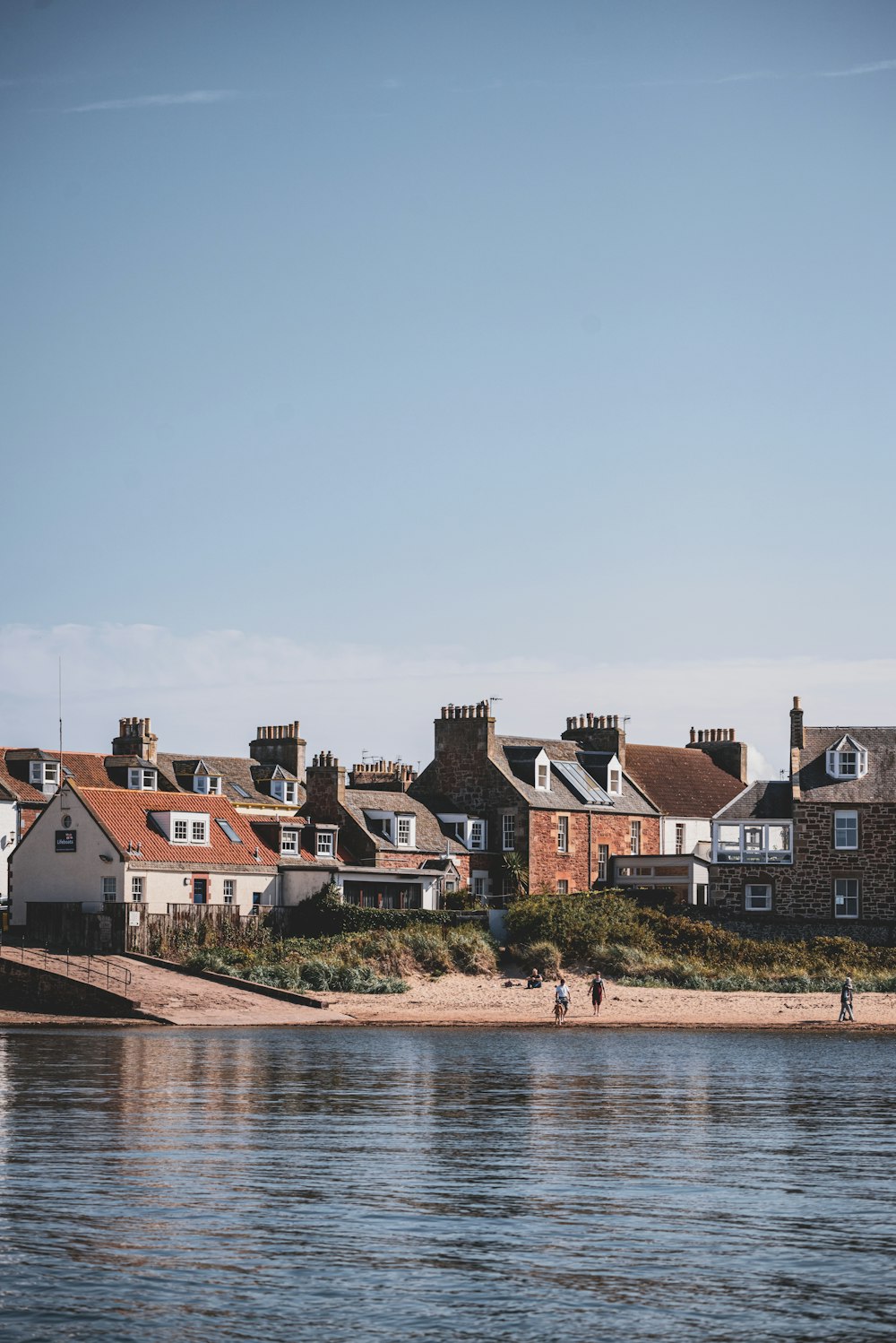 a group of houses sitting on top of a beach next to a body of water