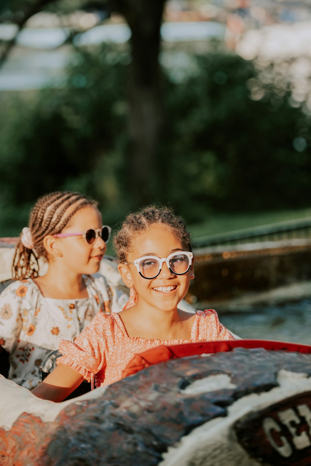 two young girls riding a roller coaster in a park