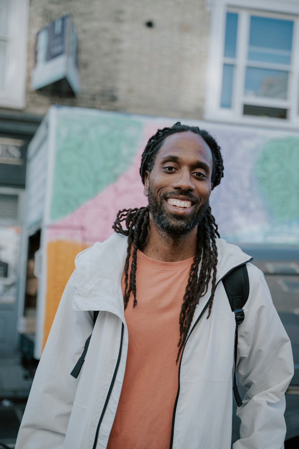 a man with dreadlocks standing in front of a building