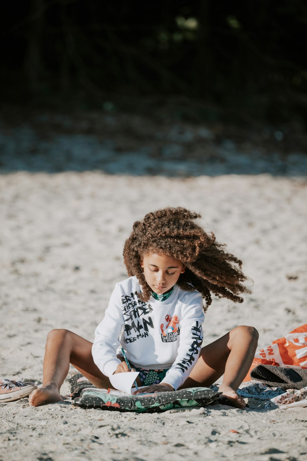 a little girl sitting on the sand with a surfboard