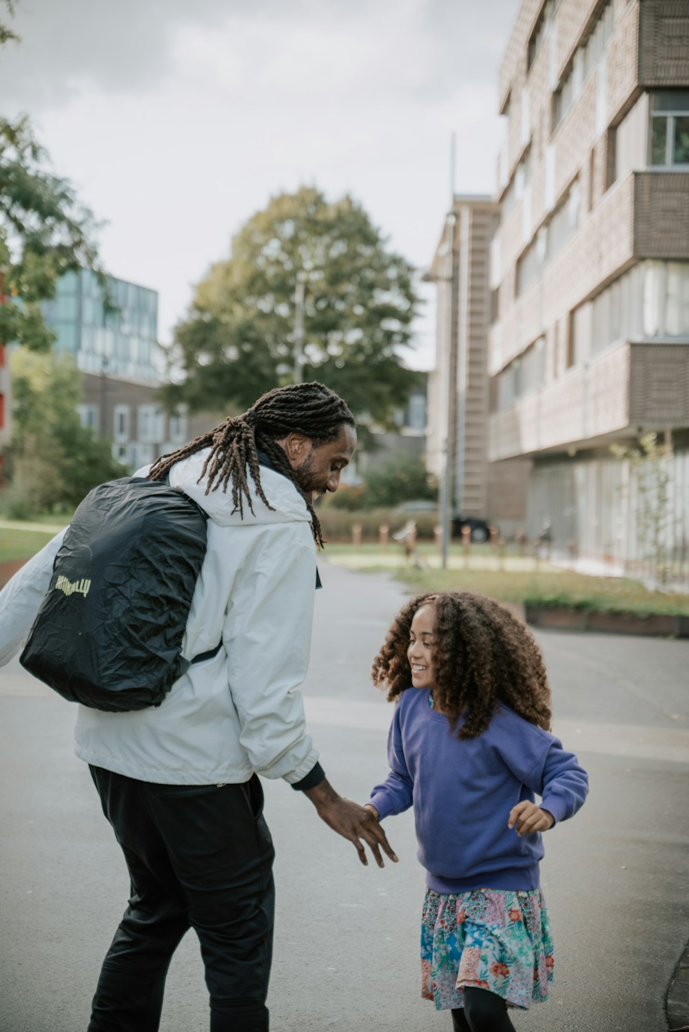 ein Mann mit Dreadlocks, der mit einem kleinen Mädchen spazieren geht