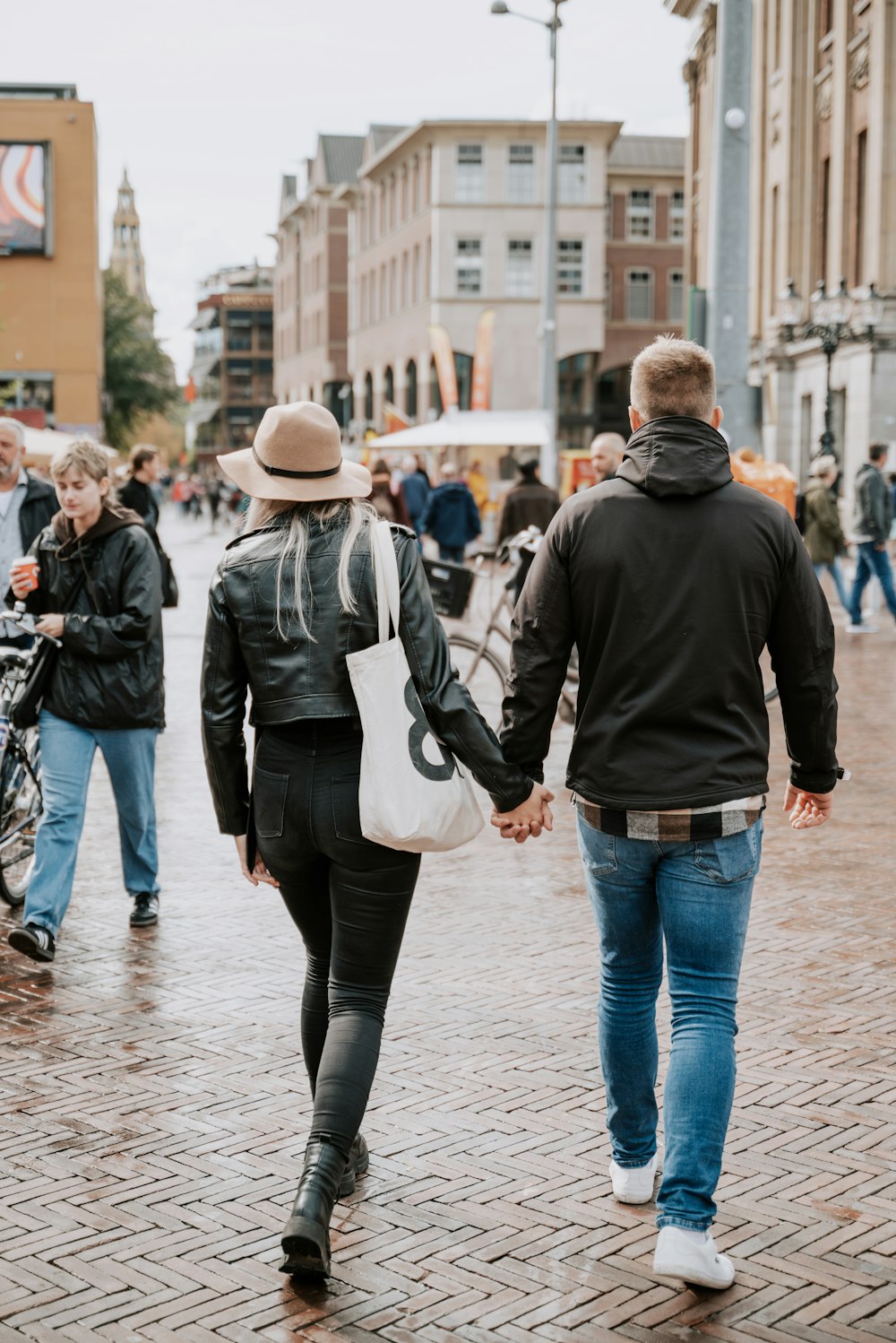 a man and a woman walking down a street holding hands