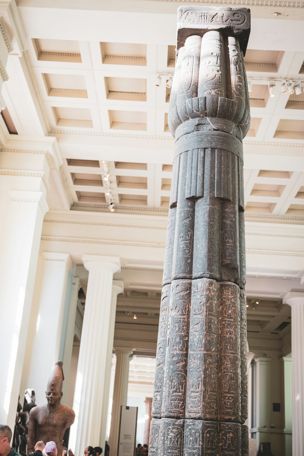 a tall statue in a museum filled with people