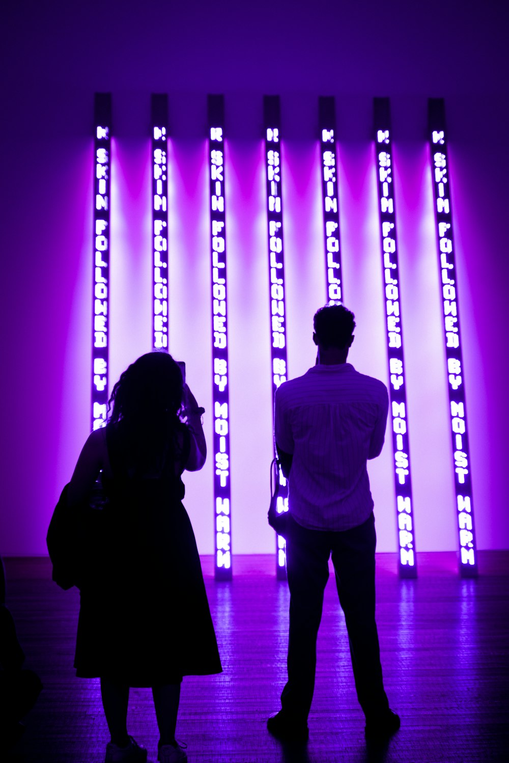 a man and a woman standing in front of a purple light
