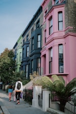 a group of people walking down a sidewalk next to tall buildings