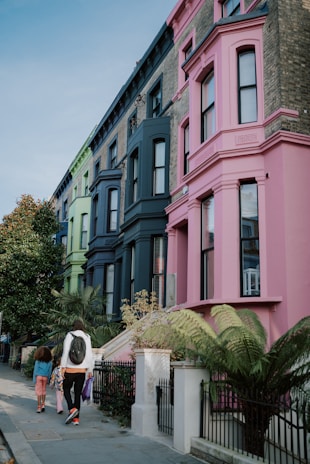 a group of people walking down a sidewalk next to tall buildings