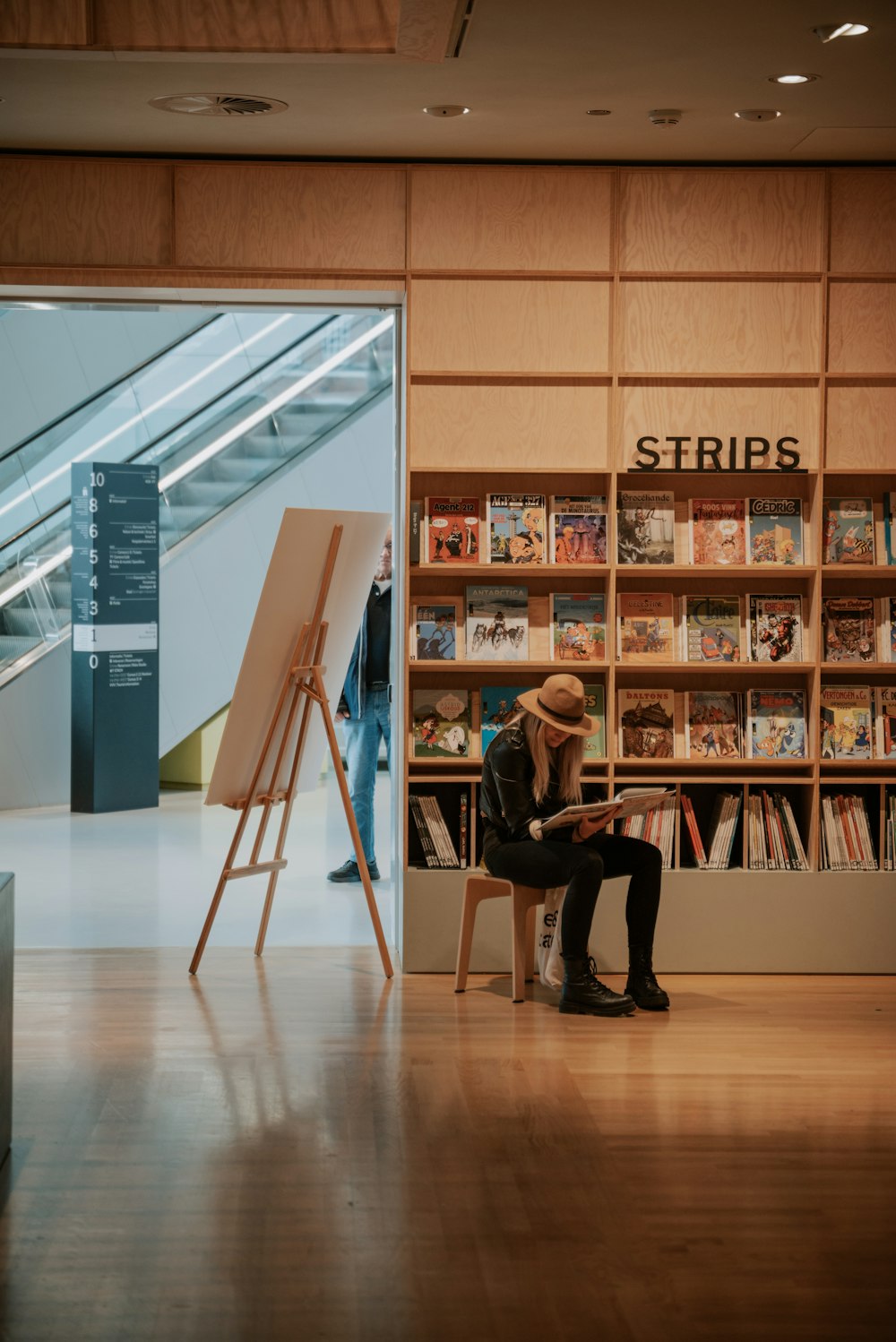 una persona seduta su una sedia davanti a uno scaffale di libri