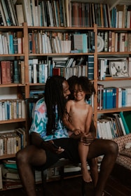a man and a woman sitting on a chair in front of a bookshelf