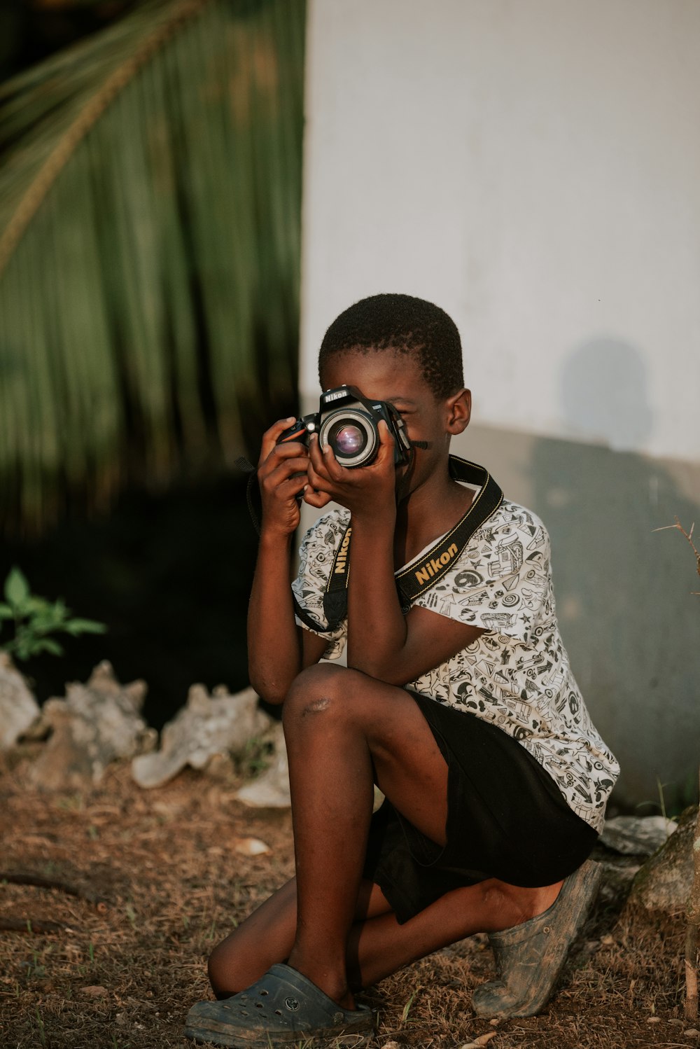 a boy sitting on the ground taking a picture with a camera