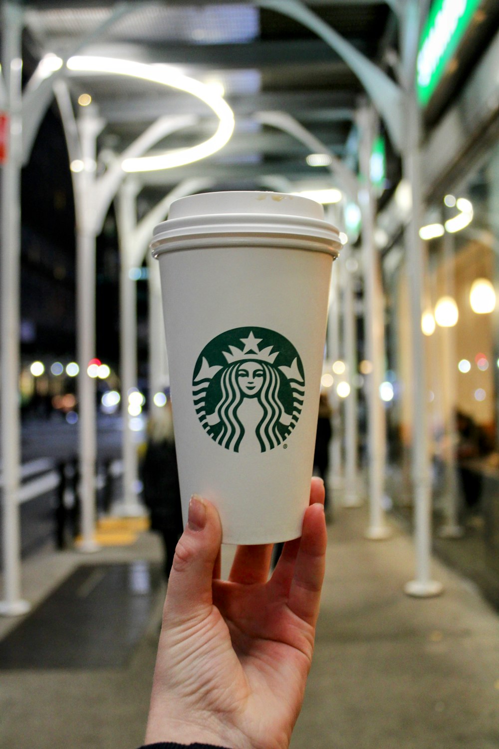 a hand holding a cup of starbucks coffee