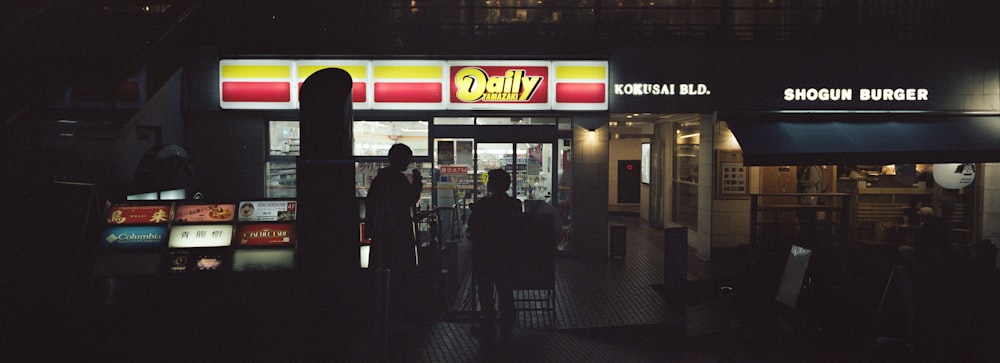 a person standing outside of a restaurant at night